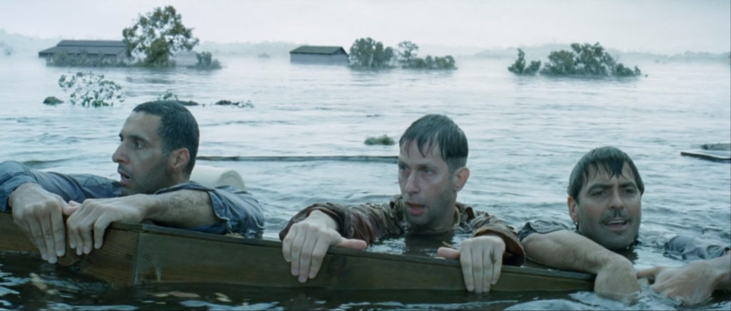 Three men hold onto a coffin as they float in a flooded valley, still from O Brother Where Art Thou