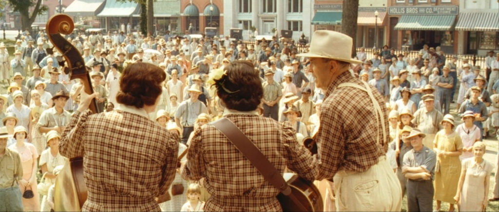 View of the back of three musicians facing an audience, still from O Brother Where Art Thou