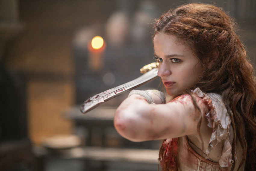 Still from The Princess (2022), close up of The Princess (Joey King) holding a sword out towards the camera